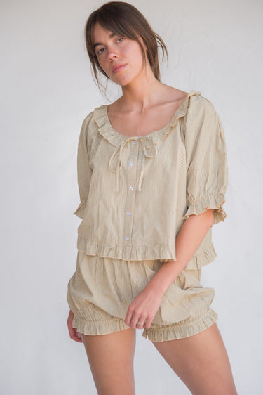 Woman wearing a green striped blouse and bloomer-style shorts set against a plain background.