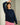 Woman wearing a navy blue sweater with red striped pants, leaning against a wall.