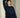 Woman wearing a navy blue sweater with red striped pants, leaning against a wall.
