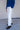 Man wearing a blue sweater with white jeans against, paired with brown boots.