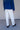 Man wearing a blue sweater with white jeans against, paired with brown boots.