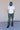 A man wearing a white t-shirt and green pants outside.