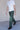 A man wearing a white t-shirt and green pants outside.