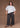 Woman wearing a white t-shirt and black pants against a brown background.
