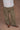 Close-up image of a woman wearing army green military-style pants on a tan background.