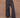 Close-up image of a woman wearing black military-style pants on a tan background.
