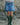 Person wearing a denim skirt and green wellington boots standing against a rocky background