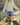 Person wearing a white cable knit sweater, blue denim skirt, and green rain boots on a rocky beach.