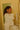 A woman looking at herself in a mirror, wearing a white long-sleeved blouse and matching pants.