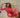 Woman sitting on a couch indoors and wearing a red blouse and pants set.