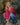 Woman in a red shirt and blue jeans squatting on rocks with a rocky background