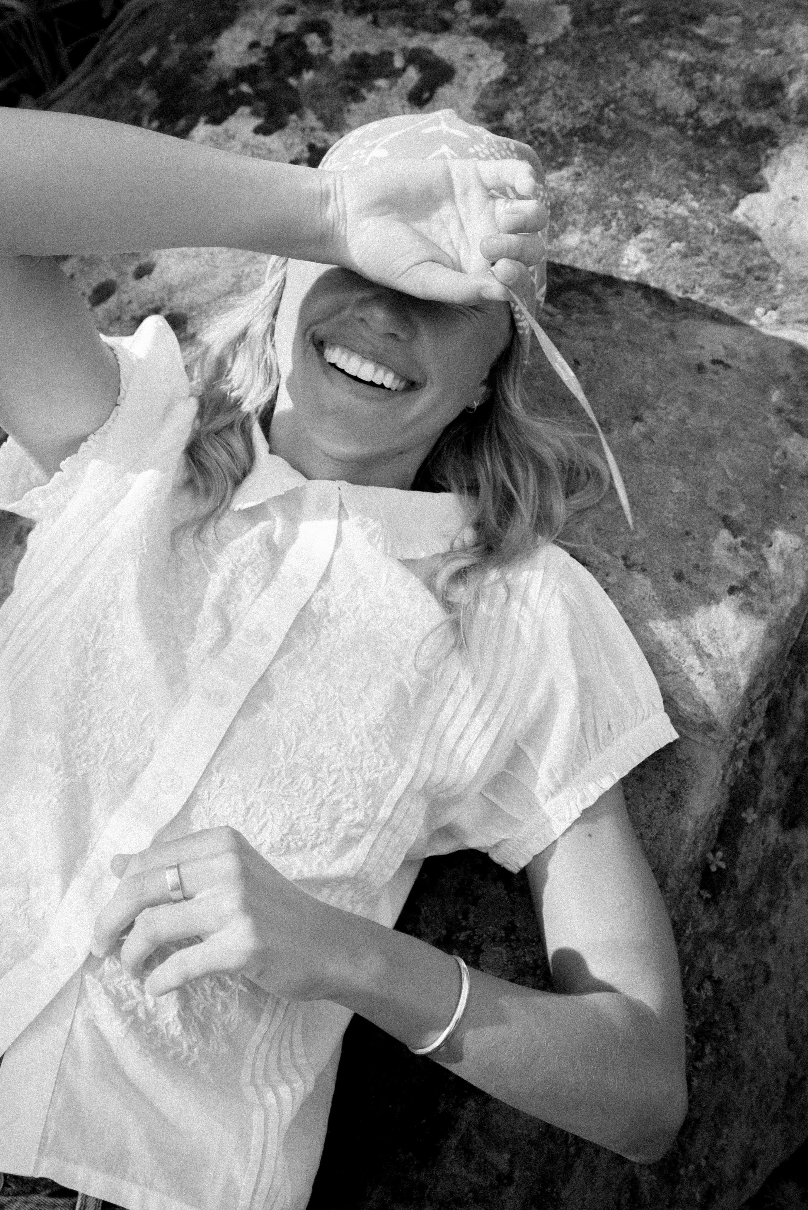 Person wearing a white dress and gloves, standing on rocky terrain.
