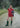 Woman in a red outfit with green boots standing on a dirt path in a natural setting
