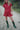 Person wearing a red outfit with green boots on a dirt path