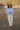 Woman standing in a field outdoors wearing a light blue wool jacket and cream pants.