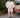 Woman in a cream cable knit sweater and pink plaid boxer-style shorts standing outdoors next to a vintage Volvo car.