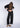 Woman wearing a black, rolled hem sweater and matching black sweater pants on a white fabric background.