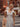 Woman in a polka dot dress holding a tote bag on a city street.