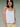 Woman wearing a white tank top and yellow pants on a plain background.