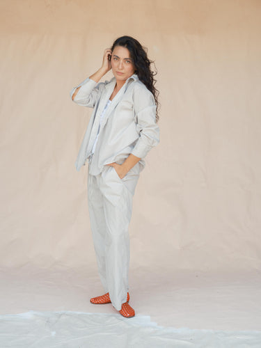 Woman wearing a light gray outfit with red shoes on a plain background