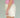Close-up of a woman wearing a pink top and cream shorts on a green background.