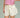 Close-up of a woman wearing a pink top and cream shorts on a green background.