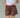 Close-up of a woman wearing a white top and brown shorts on a green background.