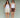 Two women standing next to each other on a green background. One woman is wearing a white tank top with cream shorts, the other woman is wearing a white tank top with brown shorts.
