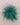A fluffy, feathery green decorative brooch, photographed from directly above on a plain beige background.