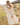 Woman wearing a cream-colored crochet knit wearing and a cream-colored skirt in a field outdoors.