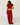 A woman modeling a matching red ribbed two-piece set consisting of a short-sleeve crop top and wide-leg pants, standing against a white wall and light wood floor.