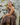 Woman in a brown dress sitting on rocks with a bandana on her head.