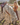 Woman in a brown dress standing next to a white horse in an open field.