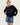 A woman modeling a black knit sweater with a large blue rectangular patch featuring a black rabbit silhouette, paired with a blue denim mini skirt, against a plain white studio background.
