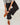 A person wearing black wide-leg ruffled pants and brown suede lace-up shoes, standing with one leg over the other.
