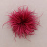 A bright magenta-pink fluffy feather accessory, centered on a plain light beige background.