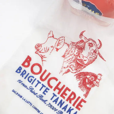 White bag with red illustrations of a cow, bull, and chicken, and text 'BOUCHERIE BRIGITTE TANAKA' on a white background.