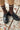 Brown knee-high socks with white stripes worn with black shoes on a concrete surface with scattered leaves.