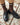 Brown knee-high socks with white stripes worn with black shoes on a concrete surface with scattered leaves.