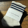 Striped sock with 'Le Bon Shoppe' label on a wooden surface