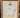 White short sleeve t-shirt with text that says "Sønderhaus" and a sideways pear graphic, hanging on a wooden hanger inside a wooden frame.