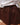 Close-up of a woman wearing a white blouse and brown skirt against a beige background.
