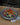 Metal tray with colorful candies and small flags on a beige surface.