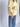 A woman bunching the sleeve of a butter yellow knit sweater paired with blue jeans.