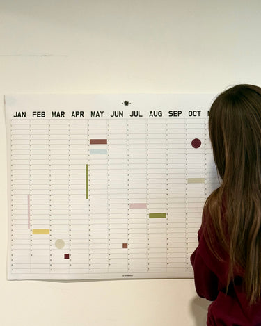 Person looking at a large wall calendar on a white wall