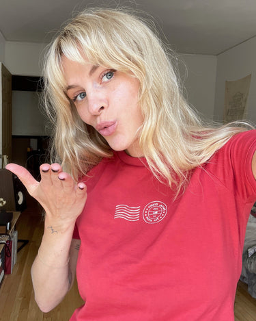 Selfie of a woman wearing a red t-shirt with white stamp-style graphics.