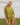 Woman wearing a green knit matching sweater and shorts set standing outdoors with a white wooden structure in the background.
