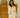 Woman wearing a yellow knit outfit standing in front of a wooden dresser.