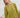 Woman wearing a green knit matching sweater and shorts set standing outdoors with a white wooden structure in the background.
