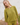 Woman wearing a green knit matching sweater and shorts set standing outdoors with a white wooden structure in the background.